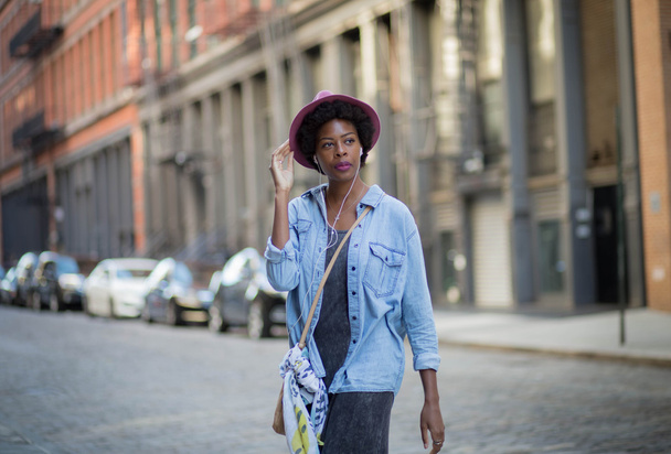 Fashionable African American woman walking and listening to musi - Fotó, kép