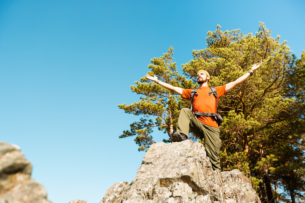 junger Mann mit Bart reist durch den Berg, Touristenrucksack steht auf Felshügel und genießt die Aussicht auf die Natur, Sommerurlaub in den Bergen - Foto, Bild