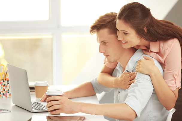 Beautiful couple surfing internet on laptop in office - Photo, Image