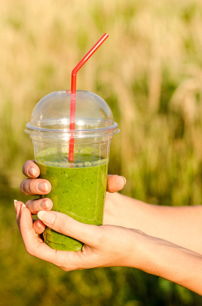 グリーン エネルギーと栄養のスムージー飲むカクテル背景に少女の手で役に立つぼやけて自然 - 写真・画像