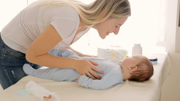 Giovane bella madre baciare il suo bambino di 3 mesi sdraiato sul fasciatoio
 - Filmati, video