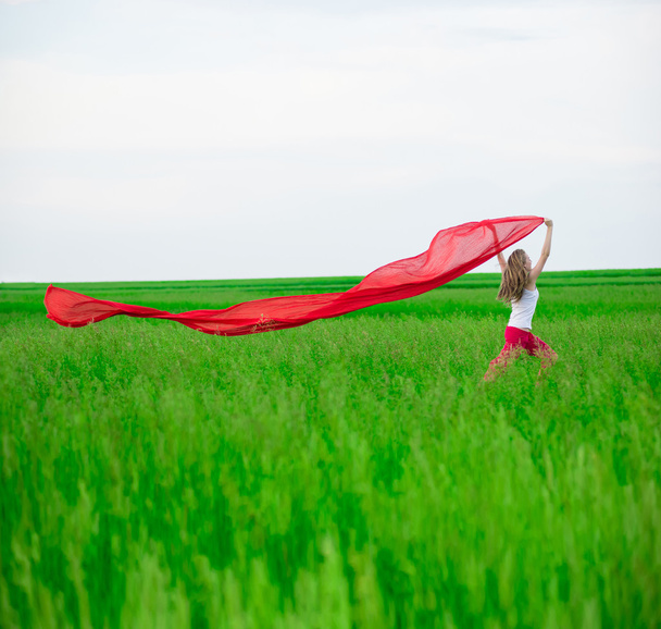 junge Frau läuft mit Gewebe auf der grünen Wiese. Frau mit Schal. - Foto, Bild