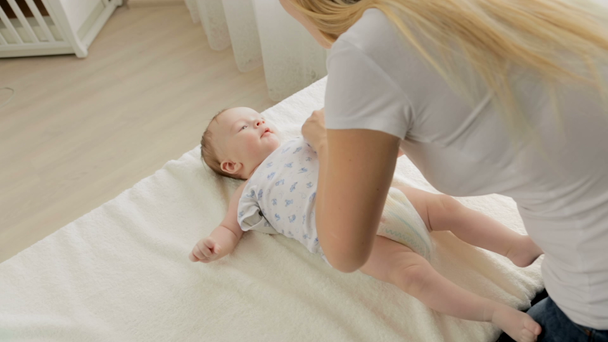 Primo piano di giovane madre spogliare il suo bambino sul fasciatoio in camera da letto
 - Filmati, video