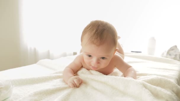 Schattig 3 maanden oude babyjongen liggend op bed en proberen te kruipen. - Video