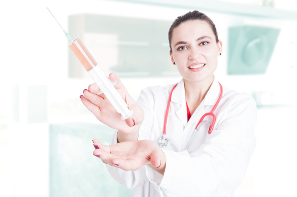 Lady medic showing big syringe - Фото, изображение