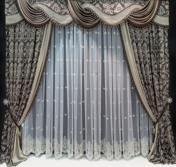 Le design luxueux des fenêtres et des murs dans un style classique. Un rideau brun avec motif floral, pelmet et un tulle transparent
. - Photo, image