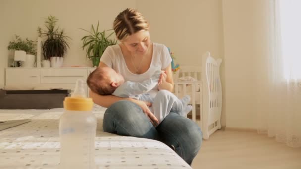 Dolly schot van gelukkige jonge moeder haar baby te slapen op bed schommelen - Video