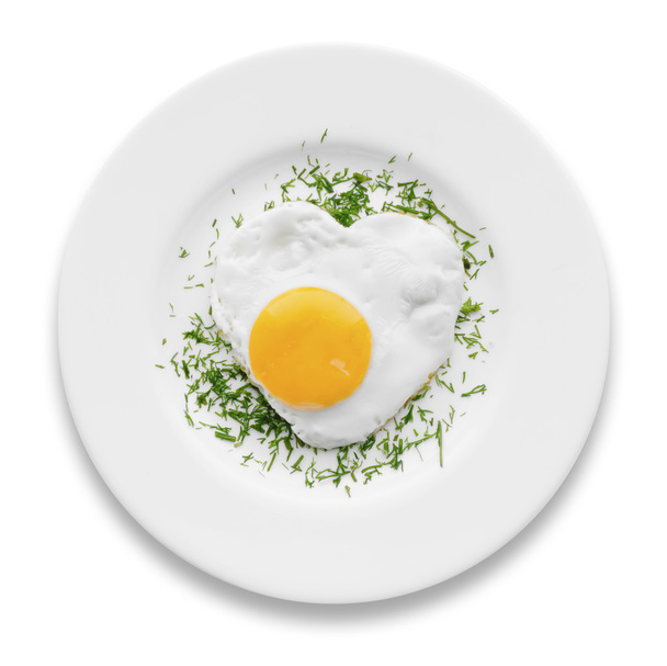 Heart-shaped fried egg with herbs on a white plate isolated - Φωτογραφία, εικόνα