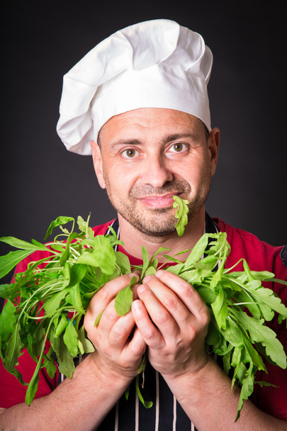 Close-up van gelukkige chef holding rucola beam - Foto, afbeelding