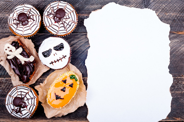 Halloween background. Old paper and funny pumpkin muffins with spiders, scull and ghost for halloween party on old rustic wooden table - Photo, Image