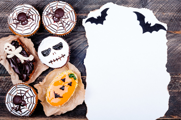 Halloween na pozadí. Starý papír s pálkou a vtipné dýňové muffiny s pavouky, vzdalovat a ghost pro halloween party na staré rustikální dřevěný stůl - Fotografie, Obrázek