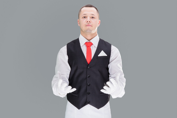 Handsome young waiter in gloves and red cravat - Fotografie, Obrázek