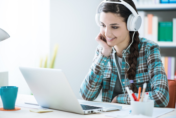 Girl with headphones using a laptop - Фото, зображення