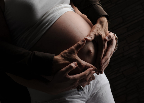 zwangere buik blootgesteld met ouders zachte handen - Foto, afbeelding