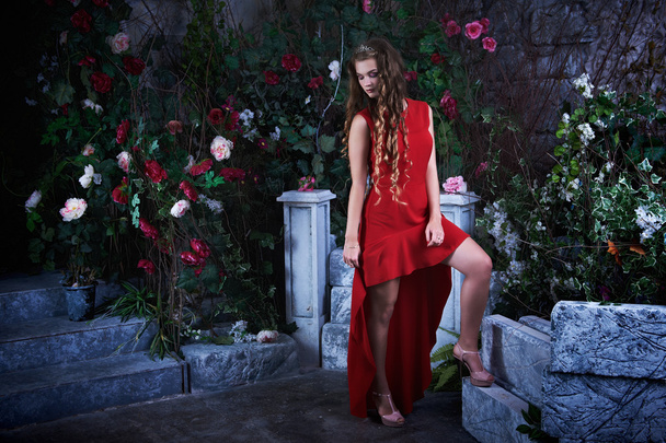 Fairy tale. Beautiful princess in red dress sitting in a mystical garden - Fotoğraf, Görsel