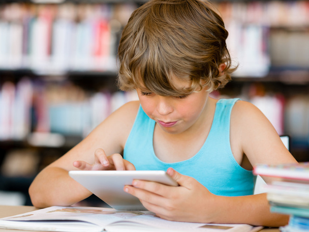 Primary school boy with tablet in library - Photo, Image