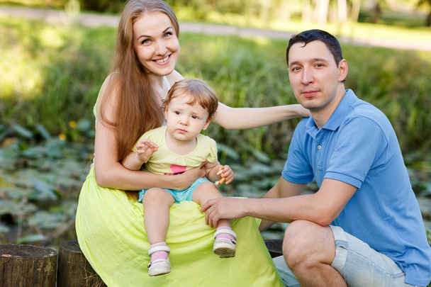 Young family in park among bushes - Foto, Imagen