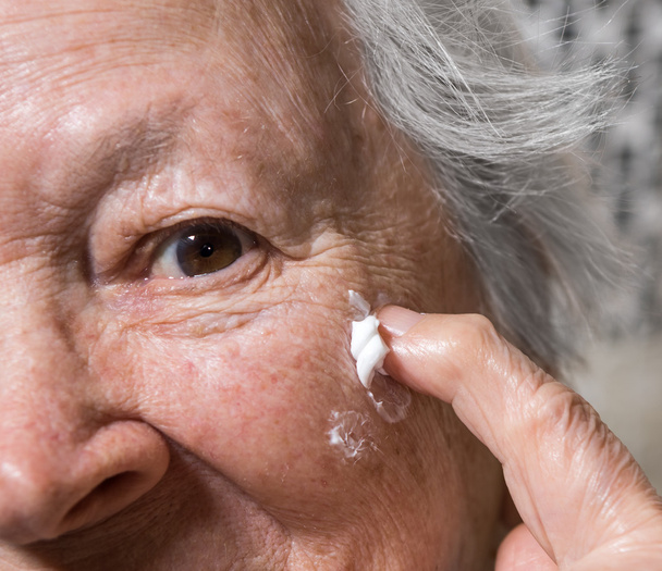 Mulher velha aplicando creme anti-envelhecimento
 - Foto, Imagem