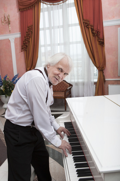 Ώριμη μουσικός παίζοντας ένα λευκό πιάνο - Φωτογραφία, εικόνα