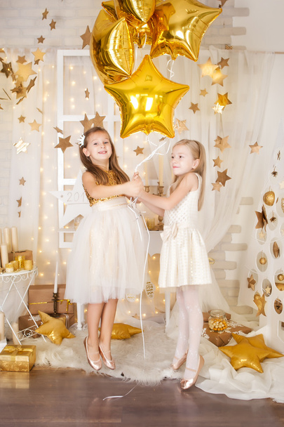 Two girls in a gold Christmas decorations - Foto, Imagen