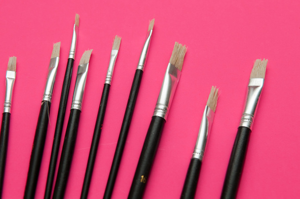 Artists brushes and pens displayed on isolated pink background - Foto, Imagem