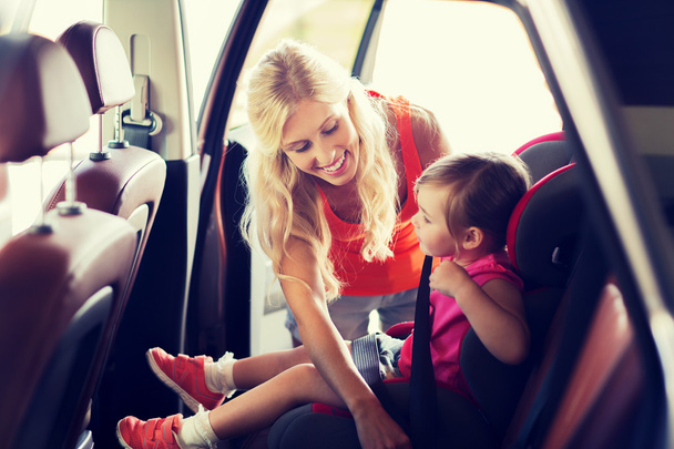 happy mother fastening child with car seat belt - Photo, image