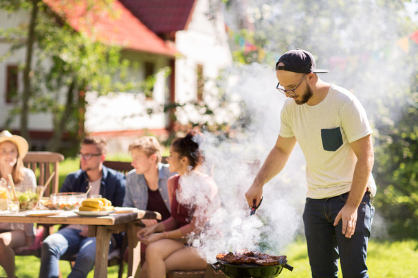 man cooking meat on barbecue grill at summer party - Photo, Image