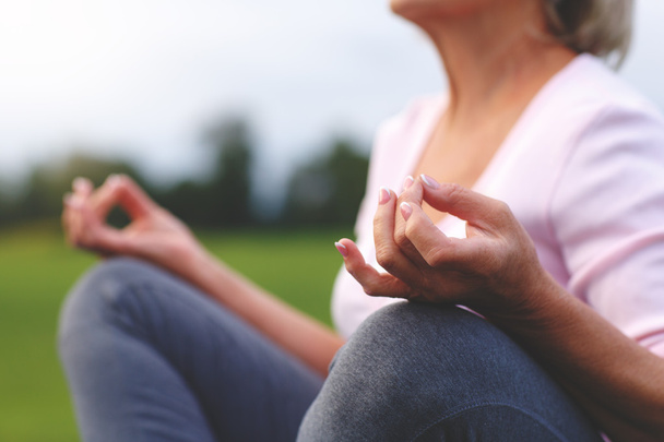 Hände einer reifen Frau, die Yoga praktiziert - Foto, Bild