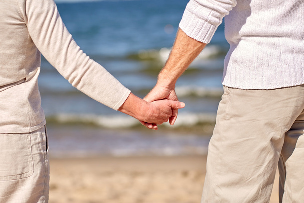 close up of senior couple holding hands on beach - Foto, Imagen