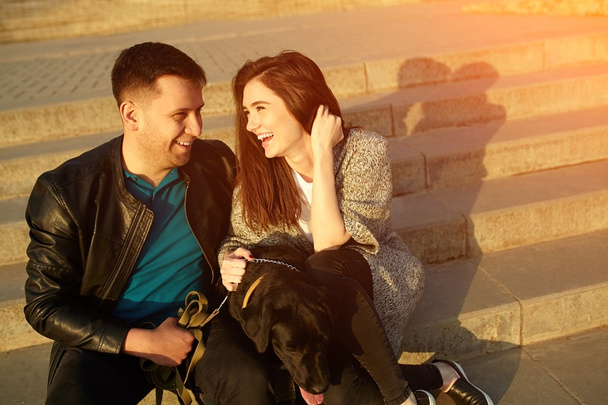 Young couple sitting on stairs with a dog - Foto, imagen