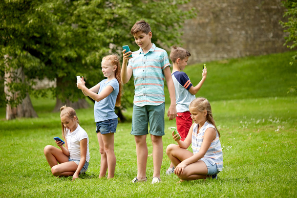 bambini con smartphone che giocano nel parco estivo
 - Foto, immagini