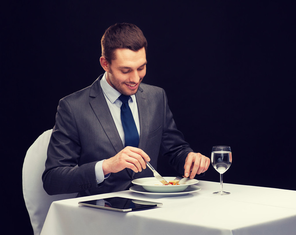 smiling man with tablet pc eating main course - Foto, Imagem