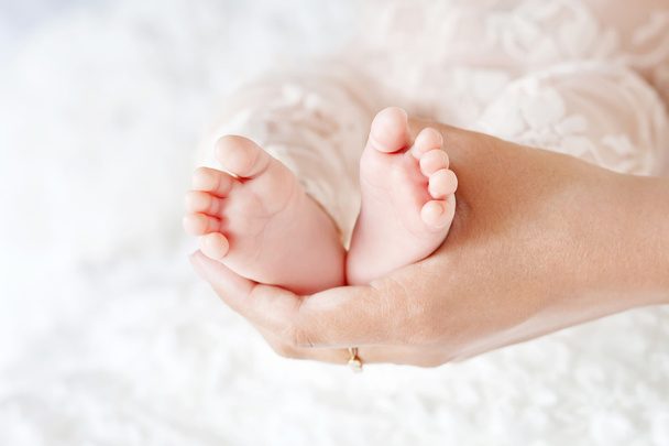 Τα πόδια το μωρό στα χέρια της μητέρας. Μαμά και το παιδί. - Φωτογραφία, εικόνα