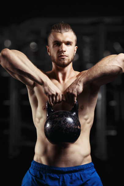 Fitness man doing a weight training by lifting heavy kettlebell - 写真・画像
