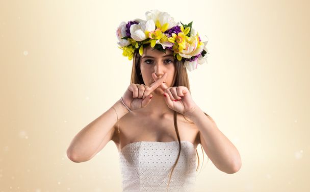 Girl with crown of flowers making silence gesture - Foto, imagen