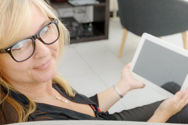 Belle femme mature utilisant une tablette électronique à la maison - Photo, image