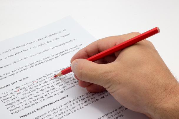 Hand beim Korrekturlesen eines fehlerhaften Textes mit rotem Stift - Foto, Bild