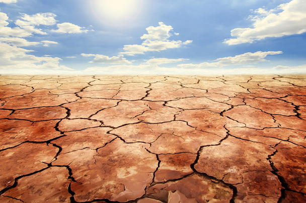 Στεγνό χώμα ραγισμένα σε ξηρασία έδαφος κάτω από το γαλάζιο του ουρανού. - Φωτογραφία, εικόνα