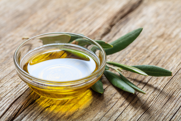 Olivový olej a olivová ratolest na dřevěný stůl - Fotografie, Obrázek