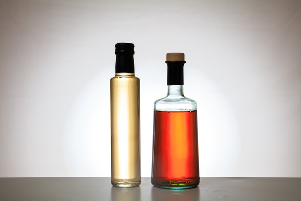 Flessen voor azijn op de achtergrond met kleurovergang - Foto, afbeelding