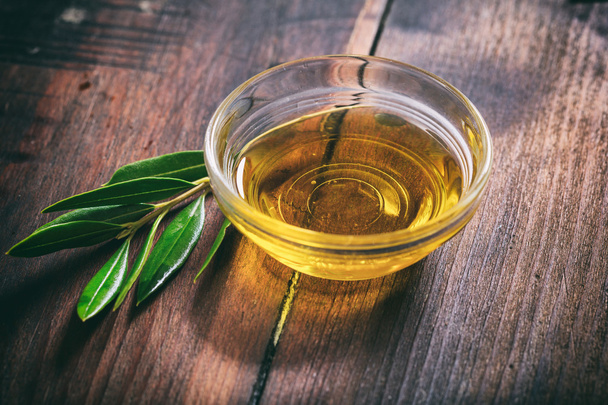 Olivenöl und Olivenzweig auf einem Holztisch - Foto, Bild