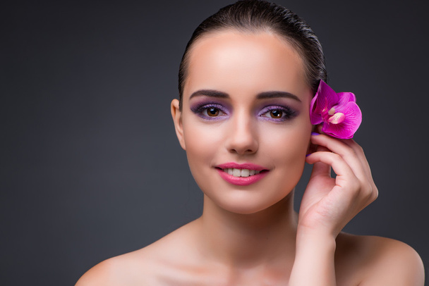 Young beautiful woman with orchid flower - Фото, изображение