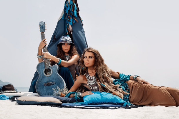 Two beautiful gypsy girls with guitar sitting on pillows at tepe - Zdjęcie, obraz
