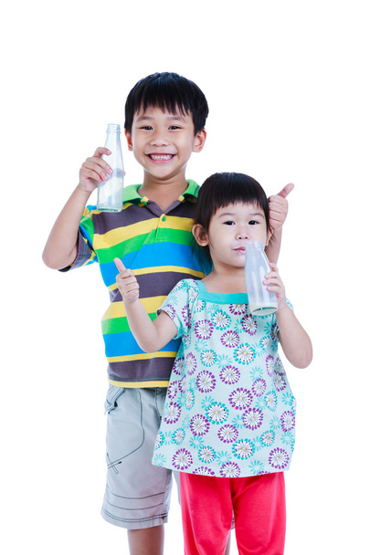 Δύο Ασίας αγόρι και το κορίτσι πίνει γάλα, απομονωμένα σε λευκό. Πίνοντας γάλα για καλή υγεία. - Φωτογραφία, εικόνα