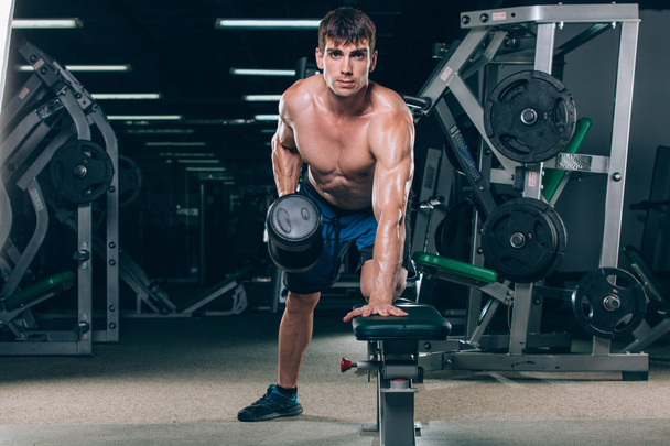 sport, fitness, lifestyle and people concept - flexing muscles with dumbbells in gym - 写真・画像