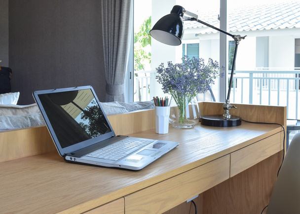 drewniany stół z komputera notebook, ołówek, lampa i sztuczne kwiaty w nowoczesne miejsce do pracy w domu - Zdjęcie, obraz