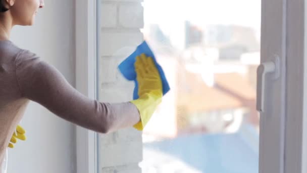Frau in Handschuhen putzt Fenster mit Lappen - Filmmaterial, Video