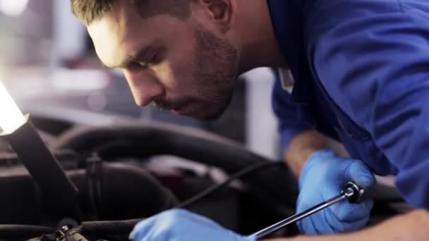 Mechaniker mit Schraubenschlüssel repariert Auto in Werkstatt - Filmmaterial, Video