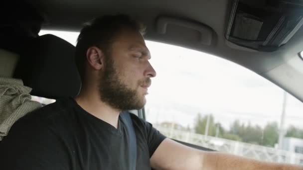 Man driving a car. Handsome man with a beard in a black T-shirt drives his car. Traveling by car. - Felvétel, videó