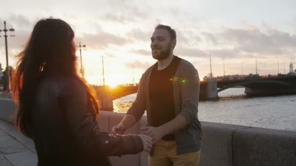 Happy couple cuddling and swirling around as the sun sets in the city. Bridge, river, road, slow mo - Séquence, vidéo